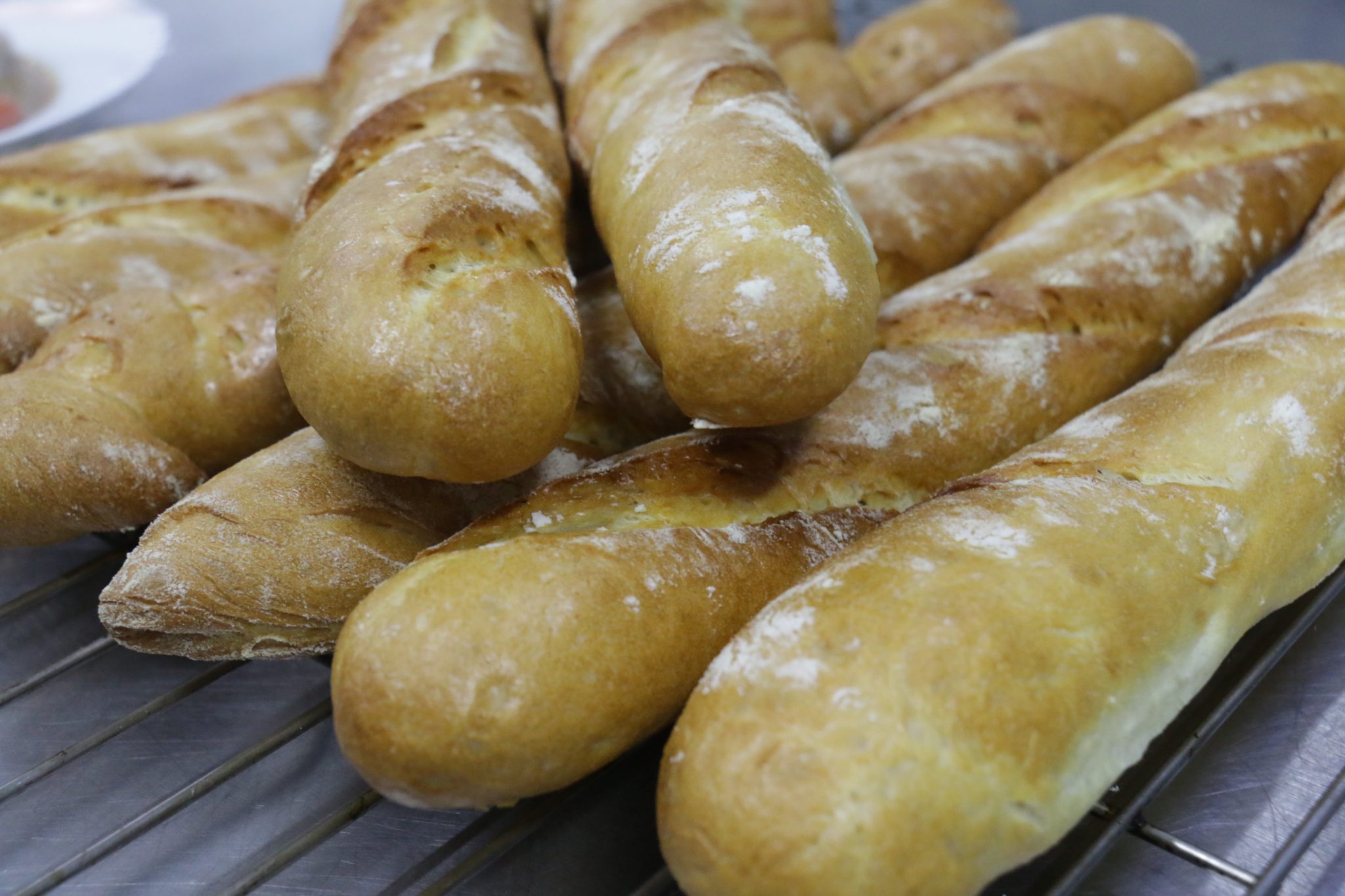 Flour-dusted baguettes cooling on a rack