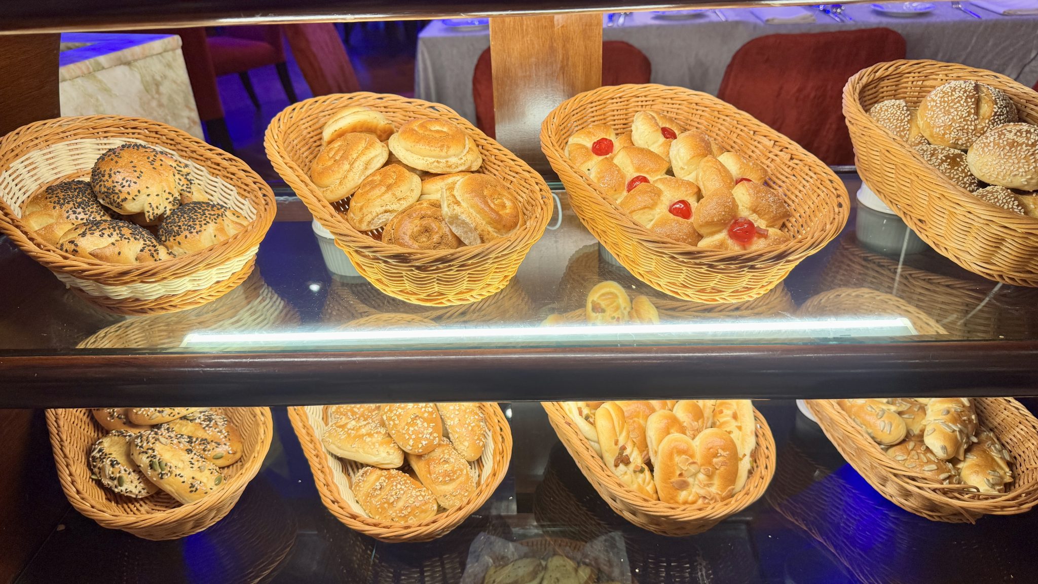 Fresh bread rolls in baskets on a bakery shelf