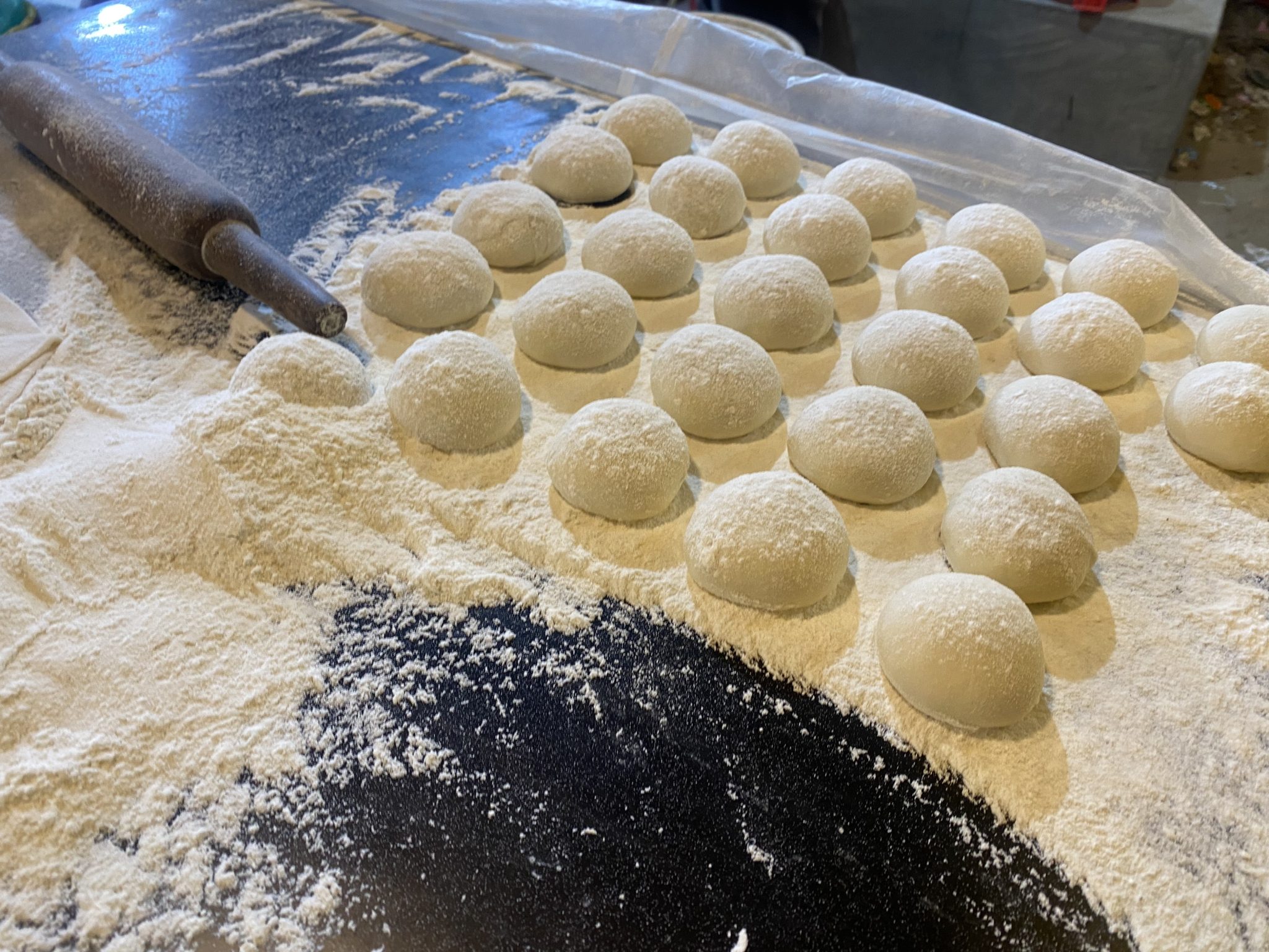 Rows of round dough balls dusted with flour