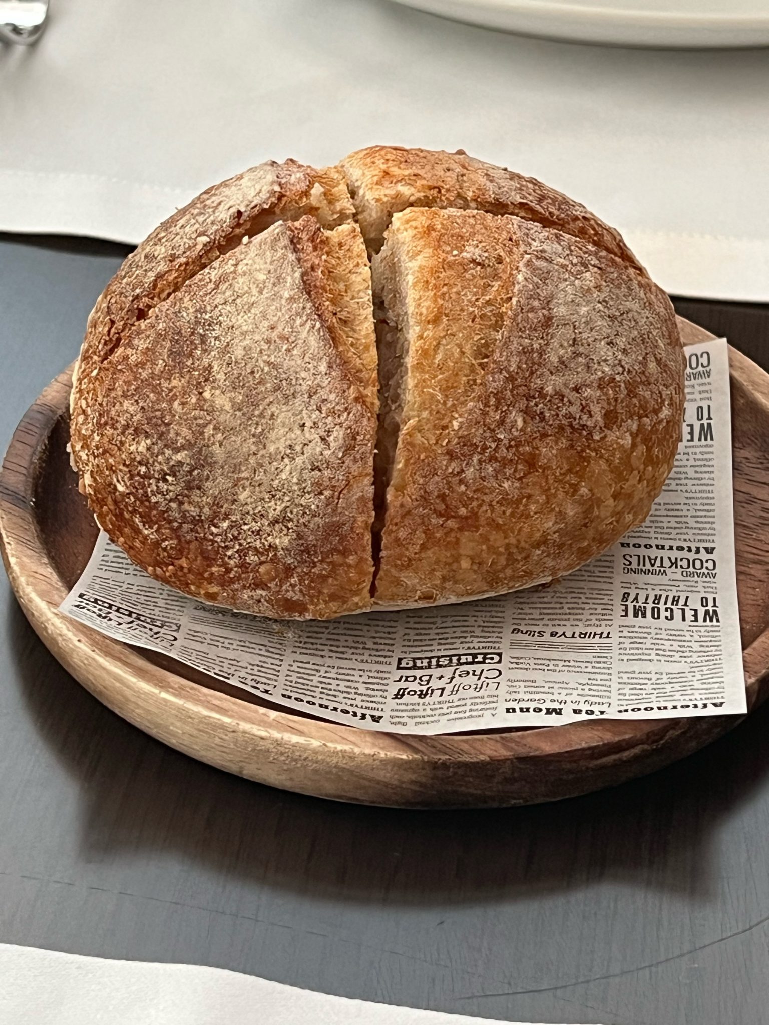 Round loaf with a cross cut in its crust on a wooden plate